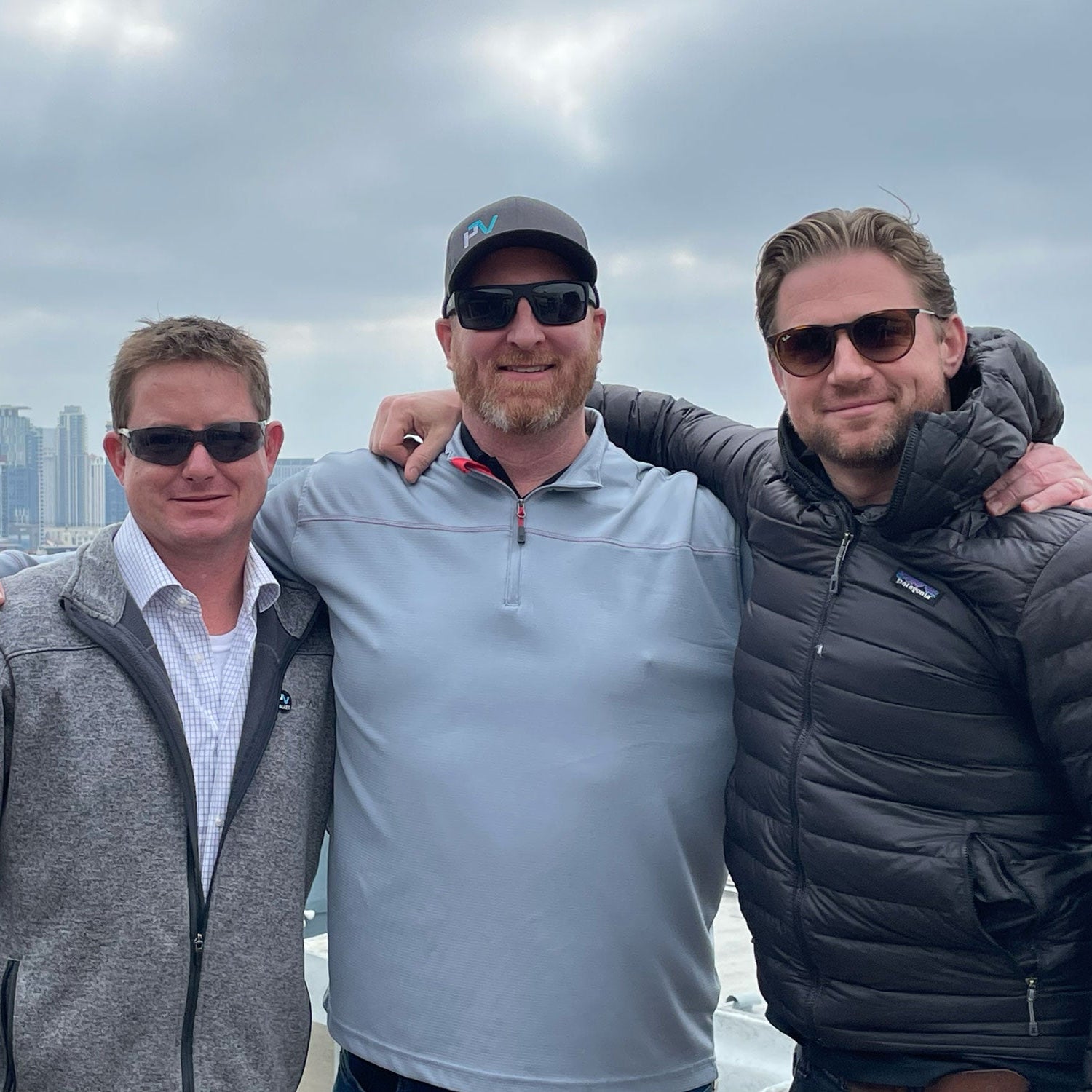 Three PVpallet team members in sunglasses pose in front of the San Diego skyline.