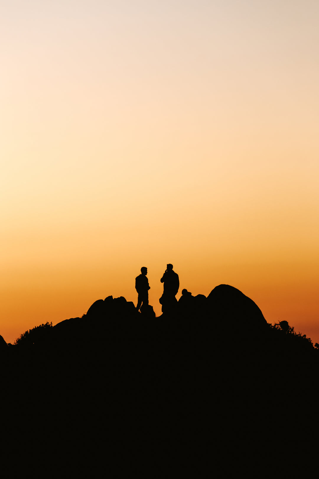 Two people standing on a hill silhouetted by the rising sun—a symbol for looking to the future with sustainable innovation.